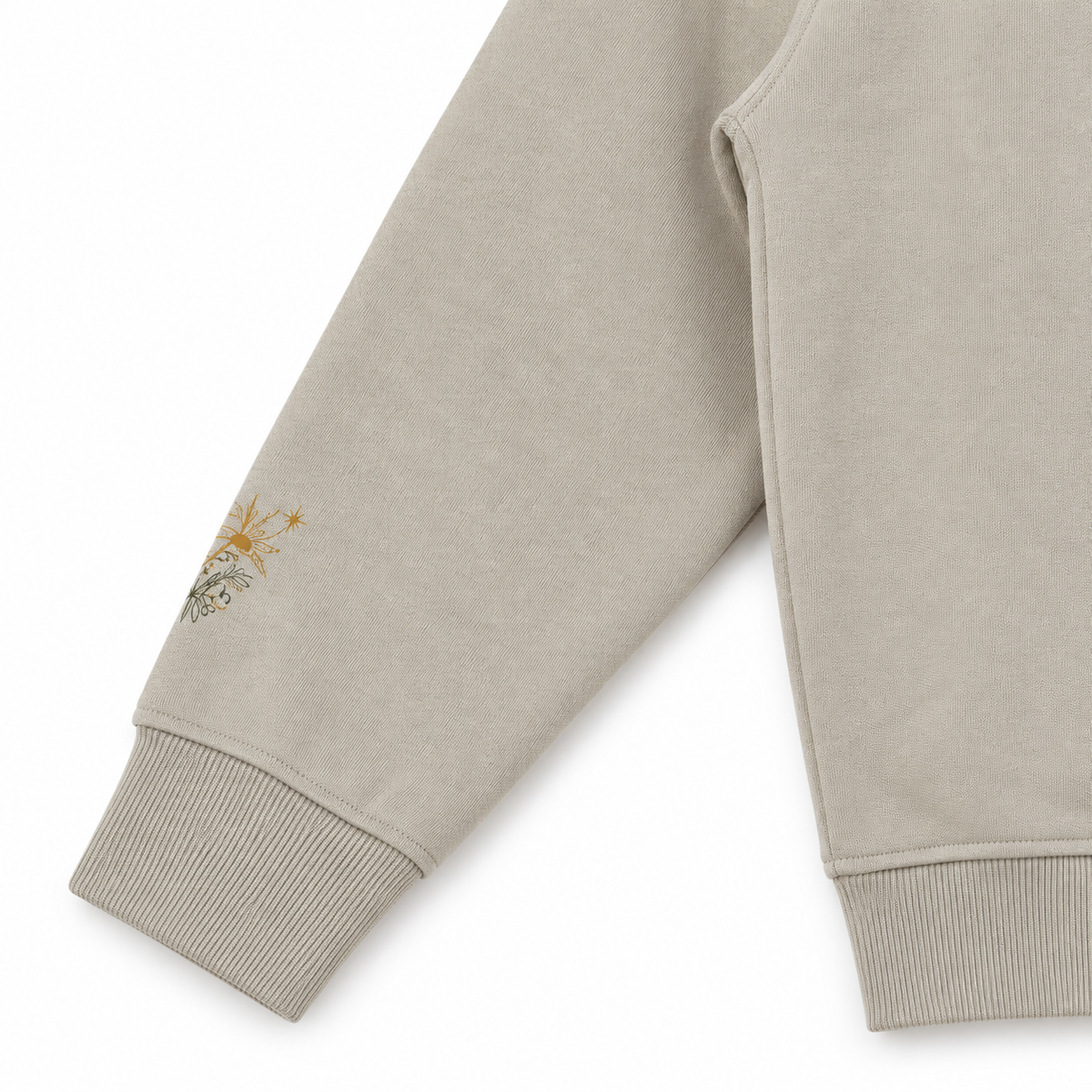 Close-up Oat Gray hoodie sleeve mockup showing the small gold botanical sprig near the ribbed cuff.